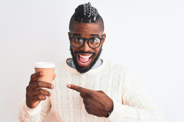 African american man with braids drinking take away coffee over isolated white background very happy pointing with hand and finger