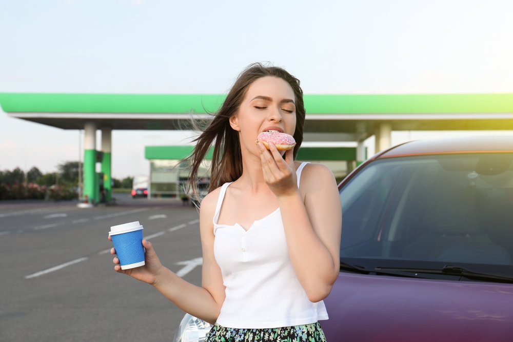 woman eating food in a gas station forecourt